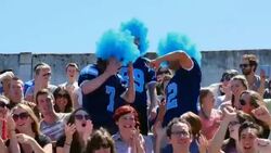 MS Three men wearing football team jerseys and wigs celebrating with other fans in stadium after team scores touchdown Stock Footage