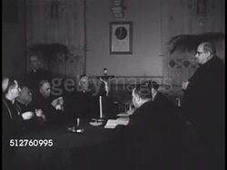 1940: VATICAN CITY: CANONIZATION: Crucifix (a cross with corpus) hanging on wall. Meeting of Cardinals, all at table inspecting sealed document. Canonization, Saint. Instructional Video