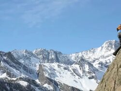 Pan to young climber scaling cliff, father congratulates him Stock Footage