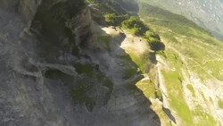 POV wingsuit flying jumping off a cliff and flying close to the rock face Stock Footage