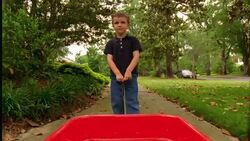 A young boy pulls a red wagon through his suburban neighborhood. Stock Footage