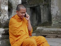 MS A Buddhist monk answers and talks on a mobile phone on the steps of an ancient temple in Angkor Wat / Siem Reap, Cambodia Stock Footage