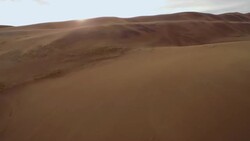 Fly up The Great Sand Dunes and pan to mountains Stock Footage