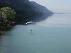 WS SLO MO AERIAL  Paramotor flying and touching a lake with his foot in the french alps / chambery, savoir, france  Stock Footage