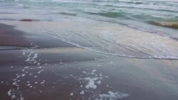 Glossy sand soaks up the sea water as waves crash on the Texas Beach on Padre Island Stock Footage