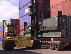 A crane lifts a shipping container above a truck. Stock Footage