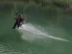 WS AERIAL SLO MO TS Shot of paramotor touching a lake with his foot in the french alps / chambery, savoir, france  Stock Footage
