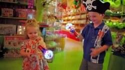 Young boy and young girl hold spinning lights in toy and candy shop Stock Footage