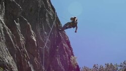 A young man repelling down a mountain while rock climbing. Stock Footage