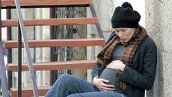 Pregnant woman sits on the stairs outdoors Stock Footage