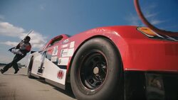 Stock car driver pulls into pit-road, pit-crew leaps into action, jacks race-car and removes lug-nuts Stock Footage