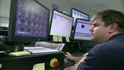 A man uses a joystick as he controls a camera and watches tube channels on a computer screen. Stock Footage
