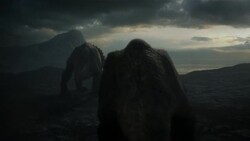 Triceratops walk across a blasted wasteland where storm clouds loom over a rocky horizon. Stock Footage