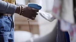Young shop employee tags shirts in clothing store with tagging gun Stock Footage