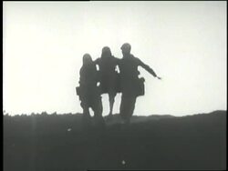 Two soldiers carry a wounded soldier down a hill. News Clip