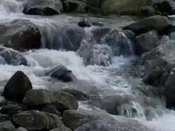 Mountain stream or river: Tilt up from water flowing over rocks and boulders to small bridge over river, Brecon Beacons, Wales Stock Footage