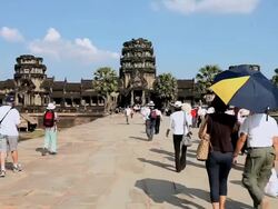 WS People walking on stone causeway leading of temple of Angkor Wat / Cambodia Stock Footage