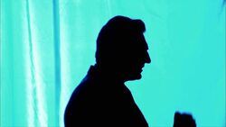 A man in silhouette standing against a blue background emphatically gestures with his hands as he speaks. Stock Footage