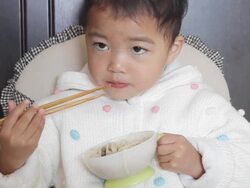 asian kid learning using chopsticks unskillfully to eat noodles Stock Footage