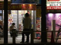 MS Shot of manga comic shop in Tokyo with pedestrians and traffic passing in front of it at night / Tokyo, Japan Stock Footage