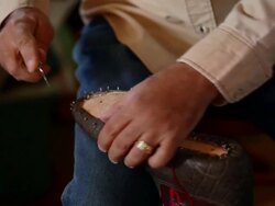 CU TD boot maker trimming excess leather from sole of cowboy boot Stock Footage