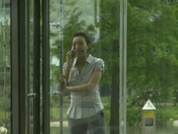 Ms female walking through door in office on phone; UK Stock Footage