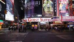 Neon lights cover the facades of buildings in Times Square as vehicles and pedestrians crowd streets and sidewalks. Stock Footage
