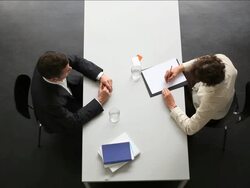 businessman and businesswoman sit towards at desk. Directly Above. Stock Footage
