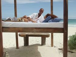 Couple lying on bed on sandy beach Stock Footage