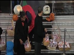 President Barak Obama and first lady Michelle Obama stood in the orange glow of the White House's northern portico on a snowy afternoon passing out Halloween treats to trick-or-treaters from capital area elementary schools and children of military families. News Clip