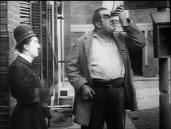 B/W 1917 policeman Charlie Chaplin hits big man (Eric Campbell) on head with nightstick /feels no pain Stock Footage