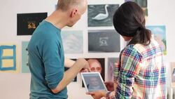 Artists discussing about a painting image using a digital tablet. Stock Footage
