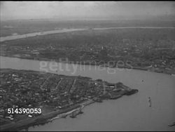 1952: NEW ORLEANS, LOUISIANA: AERIAL Angled WS Mississippi River 'S' curve winding through city, barges across from port below. HA WS Port. Angled WS Two unidenified docked ships.      Note: Specks, flecks, grainy. Instructional Video