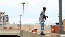 MS TS Man doing backflip off wall on building rooftop with cityscape in background Stock Footage