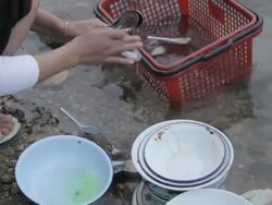 MS washing dishes in river / Xam Neua, Laos Stock Footage