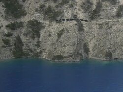 WS TD Yak caravan walking on narrow rocky cliff trail above Phoksundo lake / Himalayas, Upper Dolpo, Nepal  Stock Footage