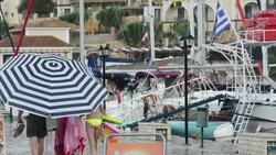 A family use a large beach umbrella to escape torrential rain and hail from a thunderstorm in Sivota, Greece. Stock Footage
