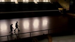 Two basketball players walk across a darkened court and high five one another. Stock Footage