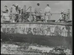 1942: PEARL HARBOR AFTERMATH:  VS Crowded United States Navy men on deck of damaged USS West Virginia after salvage, pumping water out of side of deck, damaged sides, officers talking on deck, TU from wreckage to U.S. flag flying. WWII, day of infamy Instructional Video