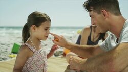 Father applying sunscreen to daughter's nose Stock Footage