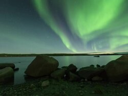 WS T/L View of summer aurora with rocks in foreground and reflection on calm lake / Yellowknife, Northwest Territories, Canada  Stock Footage