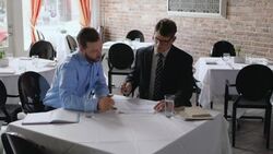 Restaurant owner discusses paperwork with financial advisor in business meeting Stock Footage