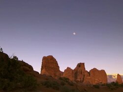 Red rock desert landscape at dusk with full moon in the empty blue sky -- pan Stock Footage