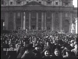 1950: VATICAN CITY: PILGRIMS: WS Piazza San Pietro (St. Peter's Square) filled w/ people standing, walking. Two Priests looking in Vatican newspaper w/ headline 'Anno Santo' (Holy Year) above photo of Pope Pius XII.  The Holy See, Catholic, Christian. Instructional Video