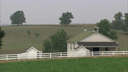 A white board fence runs past an Amish school building near Lancaster County farmland. Stock Footage
