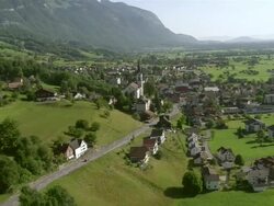 WS AERIAL View of village of gams in broad Rhine Valley with steep rock walls and summits of alpstein in background / Gams, St. Gallen, Switzerland Stock Footage