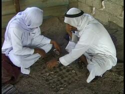 MS pair of Bedouin men sitting on floor playing game with stones set out on floor, Egypt Stock Footage