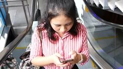 Woman texting on mobile phone on an escalator Stock Footage