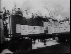 B/W 1967 crowd waving American flags on truck passing camera / "Commies Go To Hell" sign Stock Footage