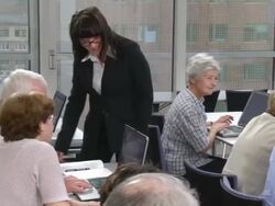 HD DOLLY: Lecturer Assisting Computer Class For Seniors Stock Footage